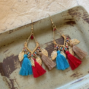 Ethnic style tassel earrings with gold filigree and colorful beads on ceramic plate