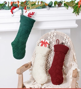 Three knit Christmas stockings in red, green, and cream with classic cable patterns