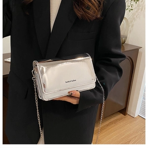 Detalle de un bolso plateado brillante con cadena metálica y acabado de espejo elegante