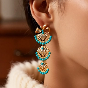 Détail macro de boucles d'oreilles vintage dorées à franges et perles turquoise