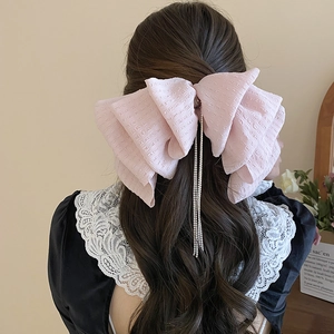 Detail of elegant pink lace bow hair clip featuring long rhinestone fringe tassels