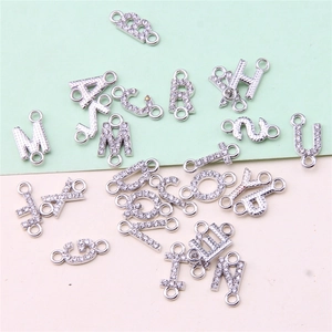Close-up of silver alphabet charms with rhinestones for DIY jewelry making