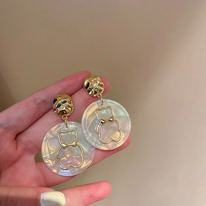 Détail du contour d'ours doré ajouré sur le pendentif circulaire blanc irisé