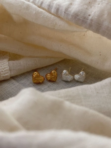Detail of heart-shaped earrings with bow relief in gold and silver finishes