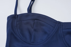 Detail of dark blue dress showing thin straps, cup stitching, and smooth fabric texture