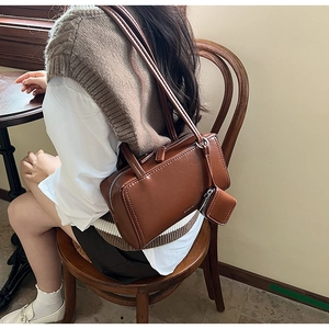 Minimalist dark brown rectangular shoulder bag shown on a model in a cafe setting