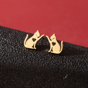 Minimalist golden cat stud earrings with hollow heart pattern on a red background