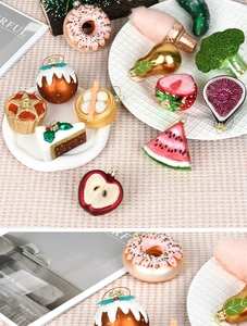 Detailed view of colorful glass Christmas ornaments shaped like food on a white plate