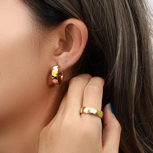 Macro shot of 18K gold plated heart enamel earrings and matching ring on a model