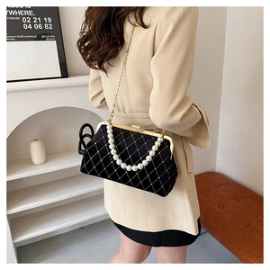 Detail of black velvet crossbody bag with quilted pattern and pearl top handle strap