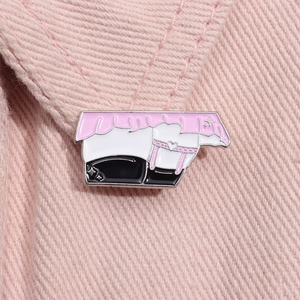Gros plan d'un badge en émail avec jupe en dentelle et bas sur un tissu rose tendre