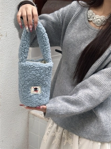 Close-up of light blue plush bucket bag with cartoon cat patch and soft furry texture