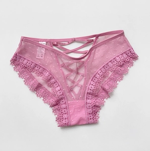 Détail de culotte en dentelle rose avec lanières croisées et motifs à pois délicats