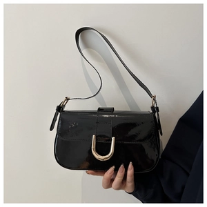 Close-up of black patent leather shoulder bag with a gold U-shaped metal buckle detail