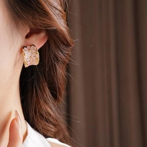 Vue détaillée de la boucle d'oreille florale en forme de C plaquée or avec émail rose
