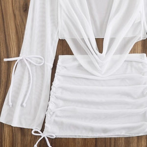 Detailed shot of white mesh long sleeve top and drawstring skirt on dark wood background