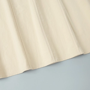 Detail of cream cotton dress hem with vertical stitching and textured fabric quality