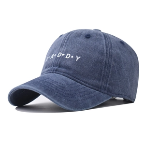 Close-up of white DADDY embroidery and playing card symbols on washed denim baseball cap