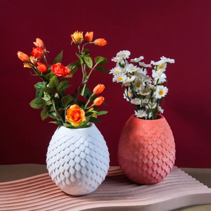 Detail of scale textured dragon egg vases in white and terracotta with floral decor