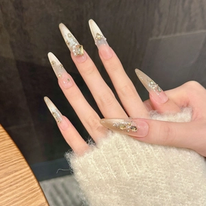Close-up of nude cat-eye press-on nails with champagne gold glitter and luxury pearls