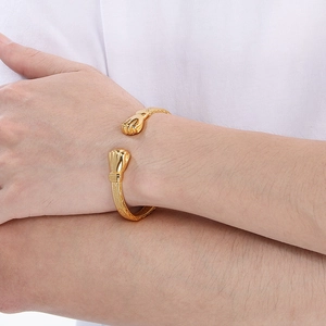 Dettaglio del bracciale rigido dorato con design a pugni e texture incise