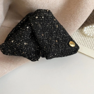 Detail of black tweed hair claw with gold sparkles and engraved 'Believe Yourself' button