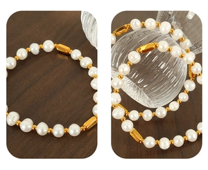 Close-up of elegant freshwater pearl bracelet with golden metal tubes on wood background