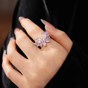 Gros plan détaillé d'une bague papillon en argent avec zircon rose sur un doigt