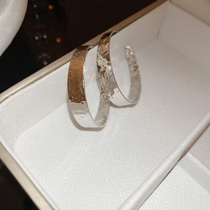 Detailed view of silver textured hoop earrings with hammered metal finish in a white box