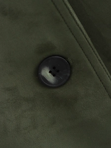 Macro detail of dark green faux suede fabric with a marble textured black resin button