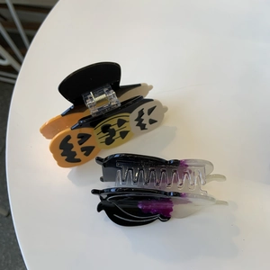 Detail of Halloween hair claws featuring pumpkin ghost patterns and purple gradient designs