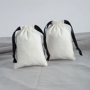 Detailed macro view of two beige cotton drawstring gift bags with black ribbon ties