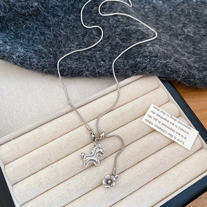 Detailed shot of horse-shaped zircon pendant with snake chain and flower charm