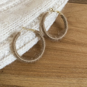 Detail of flocking round hoop earrings with brown wool texture and gold clasps