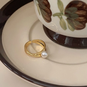 Elegant 925 sterling silver gold crossover ring with a round pearl on a vintage ceramic plate