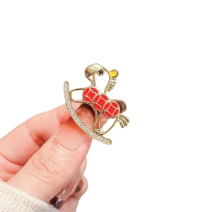 Handheld rocking horse brooch with red glaze dots and sparkling cubic zirconia stones