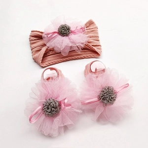 Detail of pink knitted baby headband and socks set with large mesh flower ornaments