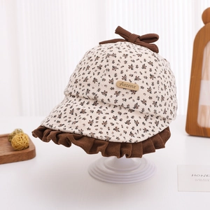 Detail of vintage baby floral sun hat with brown bow and ruffled edges on display