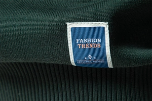 Gros plan sur la maille de coton vert foncé et l'étiquette de mode du pull pour homme