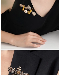 Close-up of elegant bee brooches with pearls and crystals on a black fabric backdrop