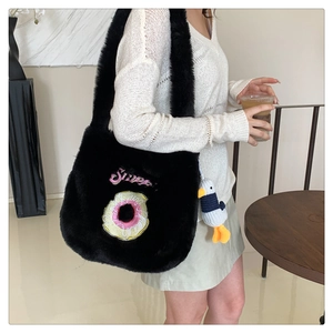Detail of black plush tote bag with sweet donut embroidery and a cute duckling pendant charm