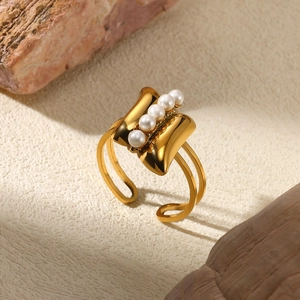 Detail of adjustable gold ring with five vertical white pearls on a textured background