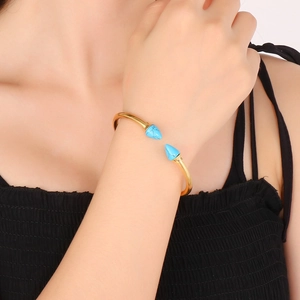 Gold stainless steel open bangle featuring turquoise studded cone ends for women