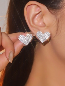 Close-up of sparkling heart stud earrings with white rhinestones on the earlobe