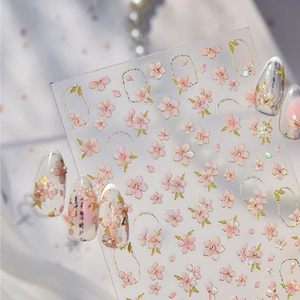 Macro detail of cherry blossom nail stickers with golden edges on clear backing sheet