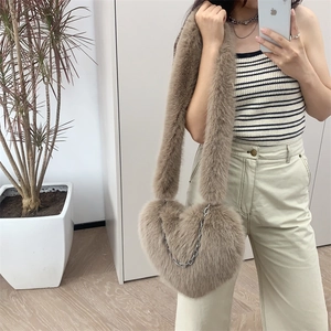 Close-up of heart-shaped faux fur crossbody bag with silver chain on a model