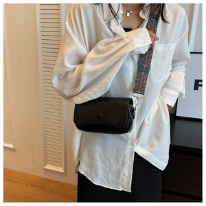 Detail of black pebbled leather crossbody bag with ethnic pattern wide strap on a model