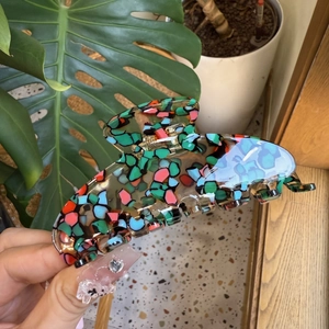 Close-up of a floral acetate hair claw clip showing vibrant mosaic patterns and smooth finish