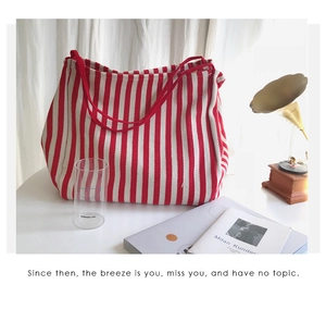 Detail view of a large red and white striped canvas tote bag in a vintage chic interior setting