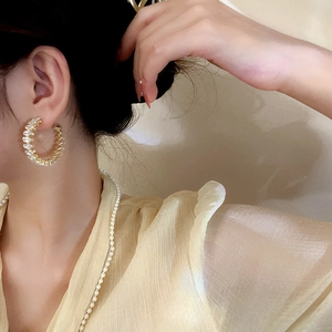 Close-up of elegant gold geometric hoop earrings with sparkling cubic zirconia on model